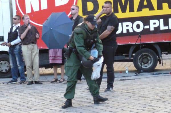 Beweissicherung: Eine Polizeibeamtin sammelt Scherben einer Flasche ein, die während der NPD-Kundgebung flog. Foto: as