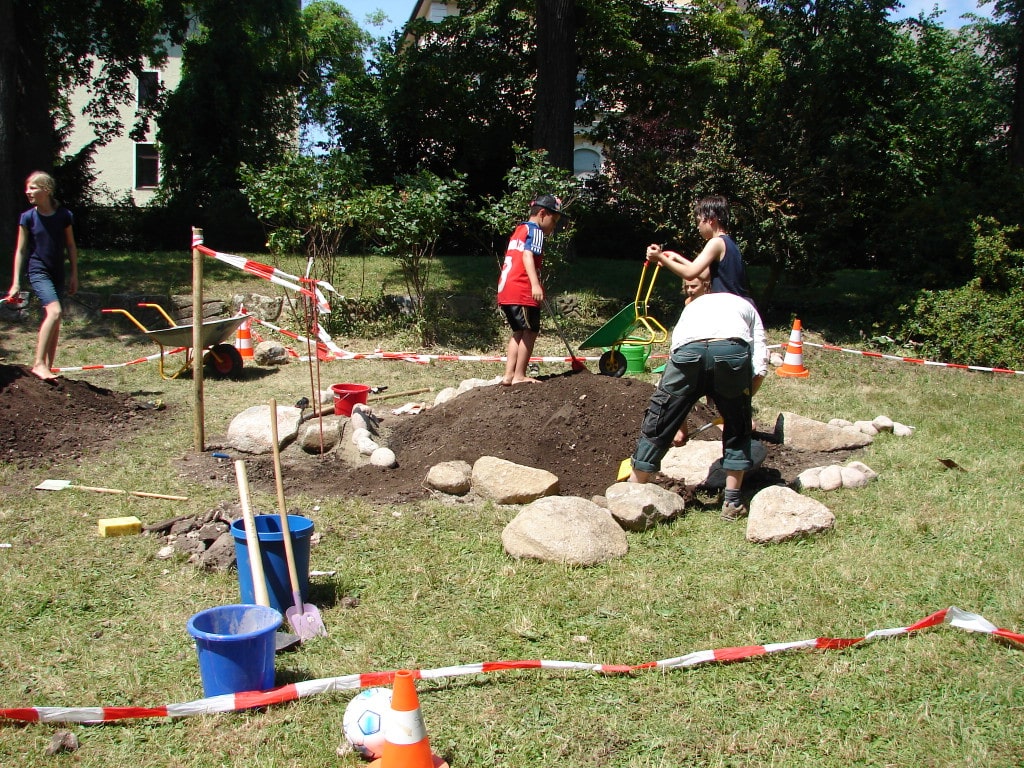 Der zuständige Landschaftsgärtner und drei fleißig helfende Kinder bei den  Bauarbeiten für die Riesenschildkröte in der Ostenallee in den Pfingstferien 2014. Foto: Boldt