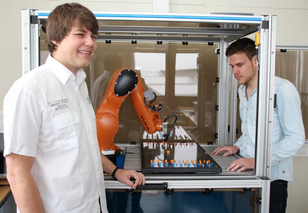 Markus Reichl (links) und Markus Webert, beides Informatik-Studierende der OTH Regensburg, lassen einen Roboter das Brettspiel Siedler von Catan spielen. Foto: OTH Regensburg