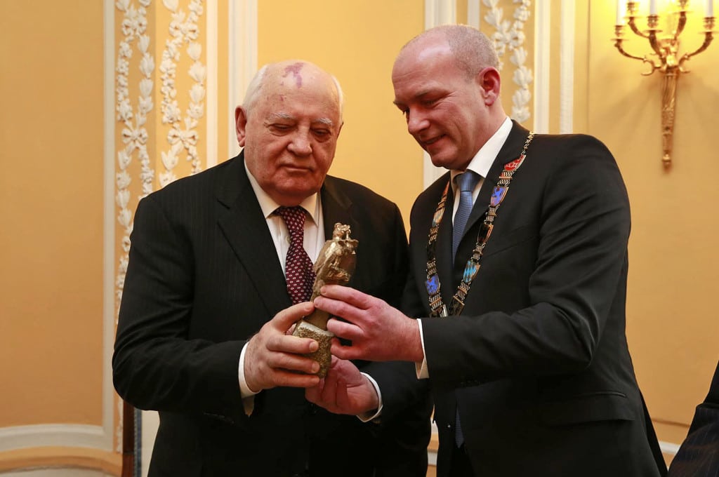 Interessiert betrachtet Michail Gorbatschow den „doppelten Nepomuk“ – eine kleine Bronzestatue, die gemeinsam mit dem Brückenpreis vergeben wird. Bildnachweis: Stadt Regensburg/Stefan Effenhauser
